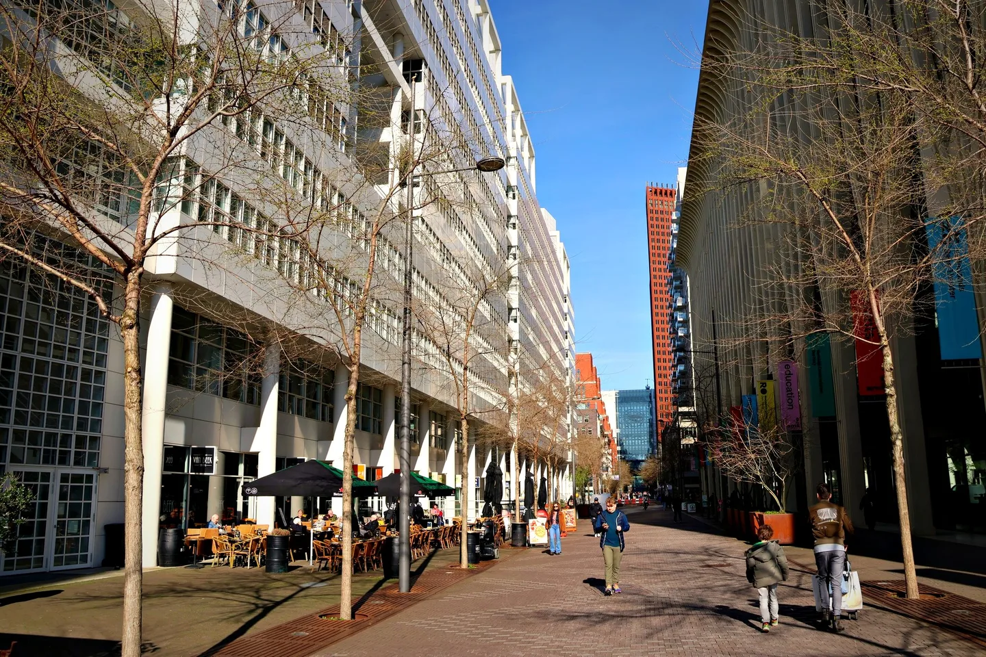 Brede stadslaan met terrasjes en modern gebouw